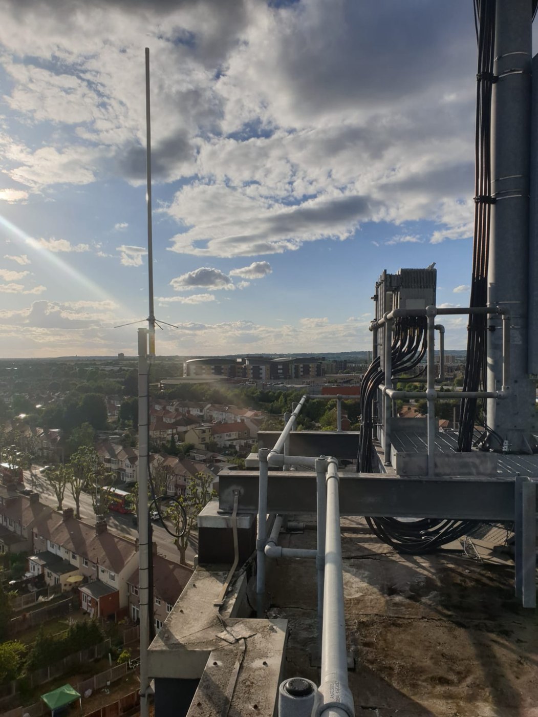 The repeater antenna alongside commercial cellular equipment and cable runs on the rooftop